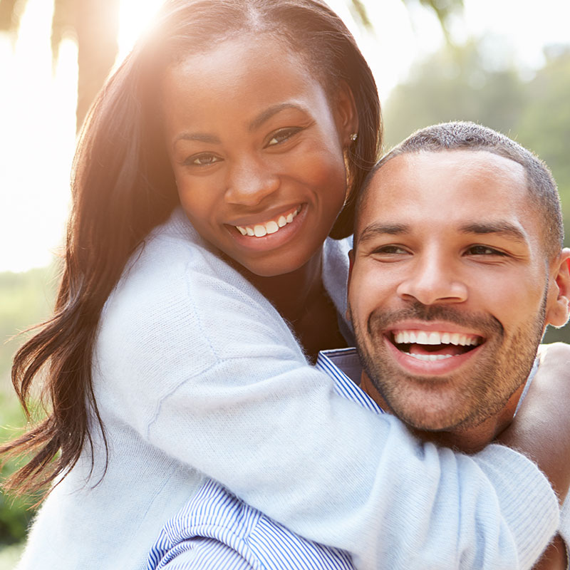 A smiling black couple during a piggy back ride. This photo represents how couples therapy Connecticut can help you improve your connection and joy in your relationship.