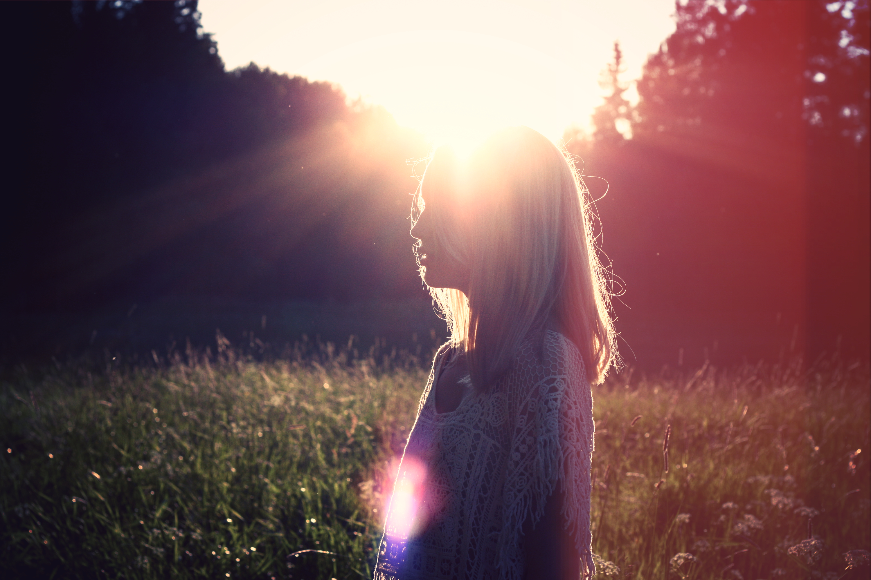 In this image, a woman stands in a sunlit field with tall grasses swaying in the breeze. She appears peaceful and content. The warm golden light of the sun illuminates her surroundings, creating a serene and calming atmosphere. The image is relevant to CBT therapy in CT as it evokes a sense of mindfulness and relaxation, which are key components of Cognitive Behavioral Therapy.