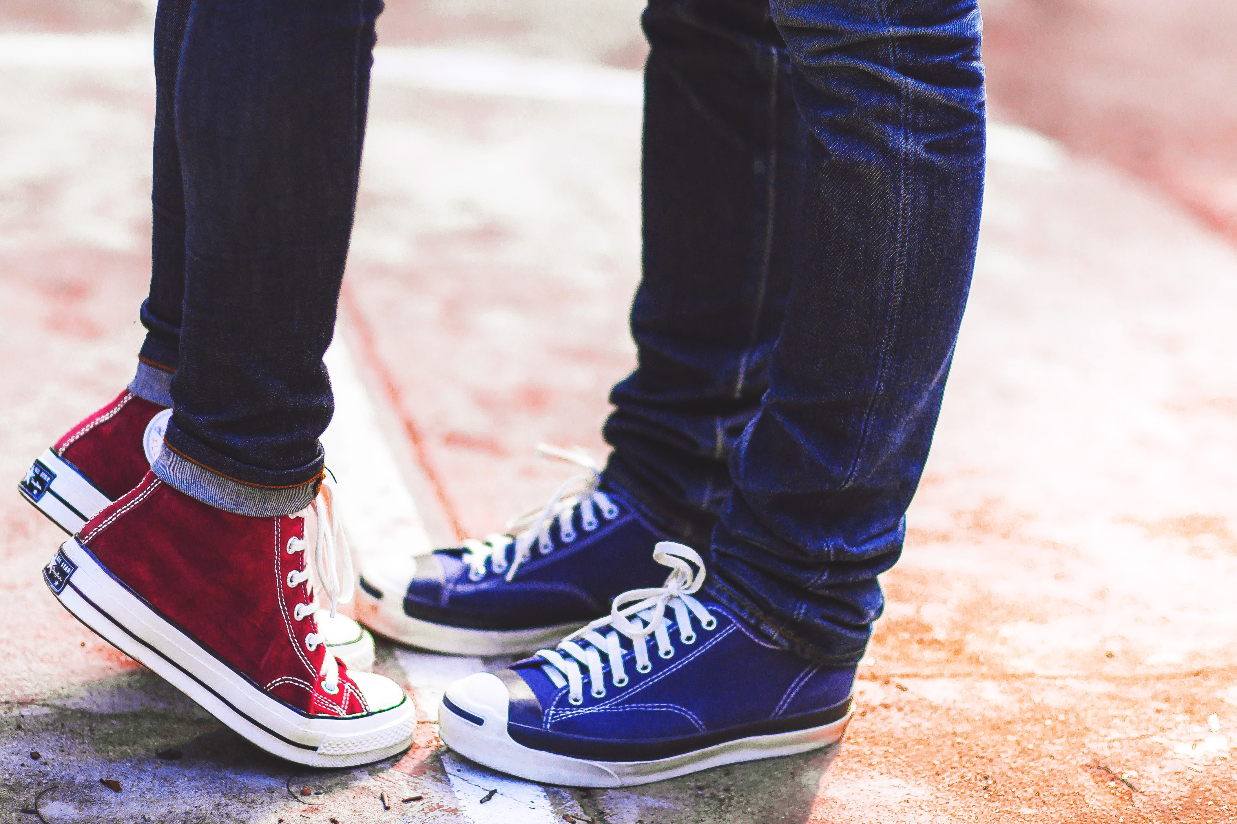 An image of two men, who are a couple and wearing matching Converse sneakers. One is on their toes as if stretching for a kiss. The image represents the importance of connection and support in LGBTQ relationships. The image promotes the idea of seeking LGBTQ therapy in Hamden, CT, where individuals and couples can work together to overcome challenges, build stronger relationships, and find support. The image evokes a sense of intimacy and the idea that with support and guidance, LGBTQ individuals can find the resources they need to live happier and healthier lives.